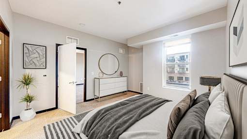 A bedroom with a large bed and a plant on the floor.