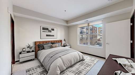 A bedroom with a large bed and a window overlooking a cityscape.