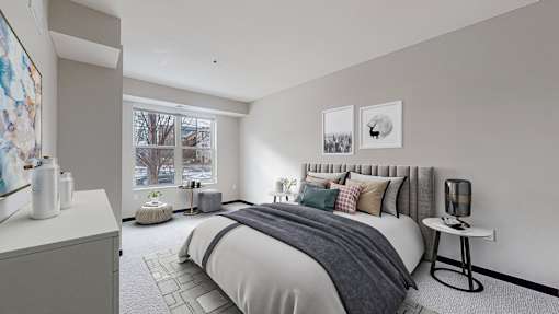 A bedroom with a large bed and a window overlooking a tree.