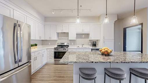 A kitchen with a granite countertop and stainless steel appliances.