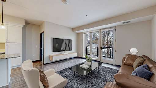 A living room with a brown couch, a white chair, and a glass coffee table.
