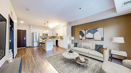 A modern living room with a kitchen in the background.