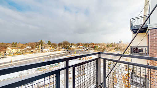 A balcony overlooks a road with cars and buildings.