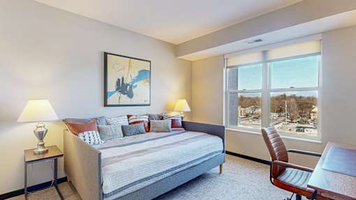 A bedroom with a bed, two lamps, a chair, and a painting on the wall.
