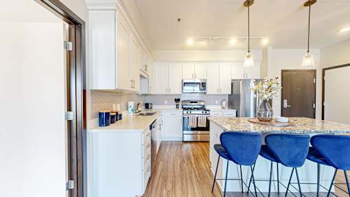 A kitchen with white appliances and blue chairs.