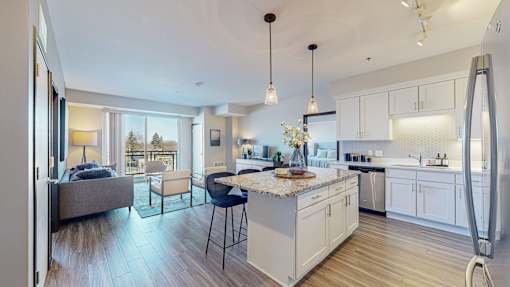 A modern kitchen with a breakfast bar and a living area with a couch and a chair.