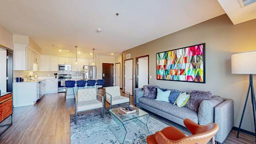 A modern living room with a grey couch and a painting on the wall.