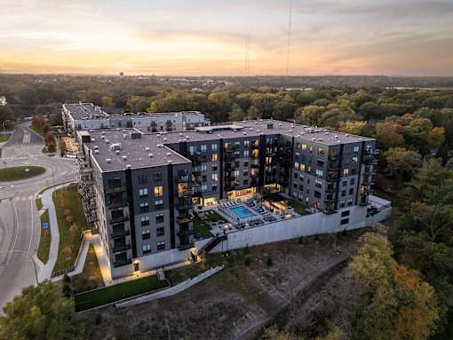 A modern apartment complex with a pool and surrounded by trees.