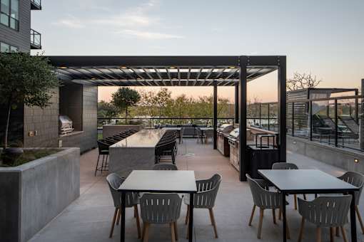 A patio with tables and chairs is set up under a pergola.