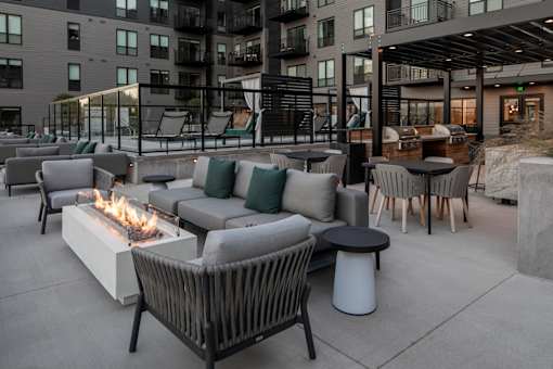 A patio with a fire pit and chairs.