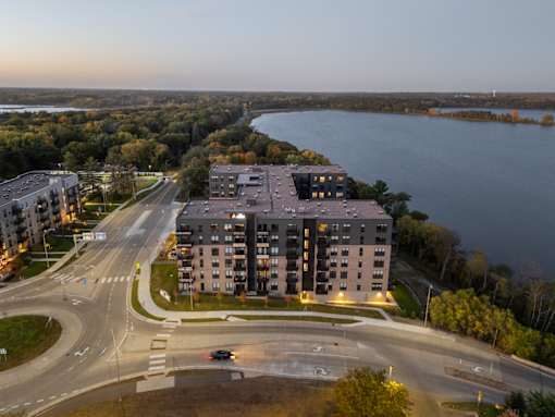 A large building is situated on a road with a body of water in the background.