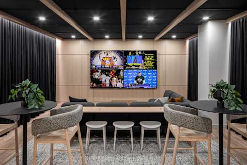 A modern living room with a large TV screen and comfortable seating.