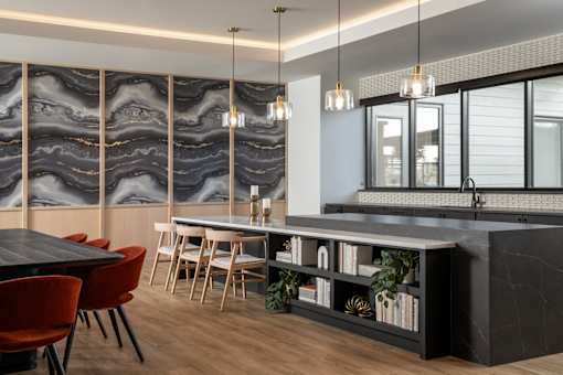 A modern kitchen with a black countertop and red chairs.