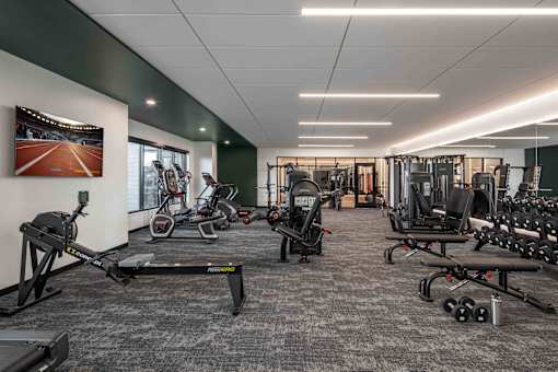 A gym with a variety of equipment including treadmills, weights, and exercise machines.