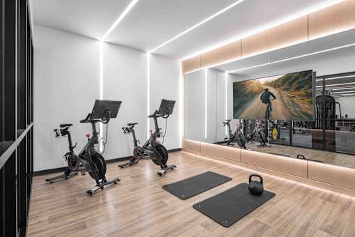 A gym with exercise bikes and a large mirror.