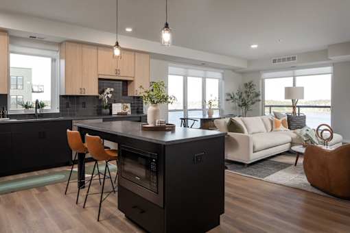A modern kitchen with a black island and wooden floors.