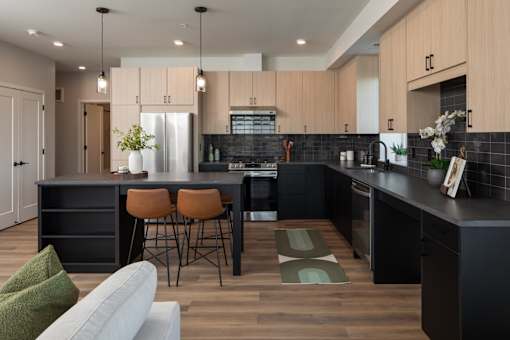 A modern kitchen with a black countertop and wooden cabinets.