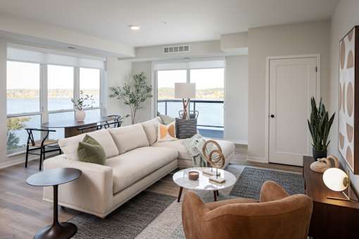 A living room with a white couch, a brown armchair, and a round table with a lamp on it.