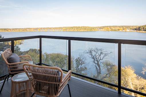 Two chairs are on a balcony overlooking a body of water.
