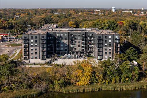 A large grey building with a lot of windows is surrounded by trees with yellow leaves.