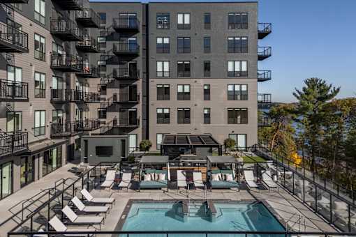 A large apartment complex with a pool and lounge chairs.