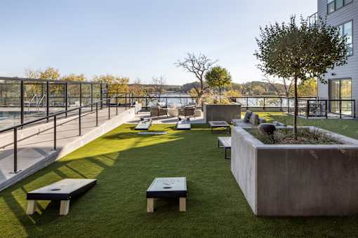 A modern outdoor seating area with concrete planters and benches overlooking a body of water.