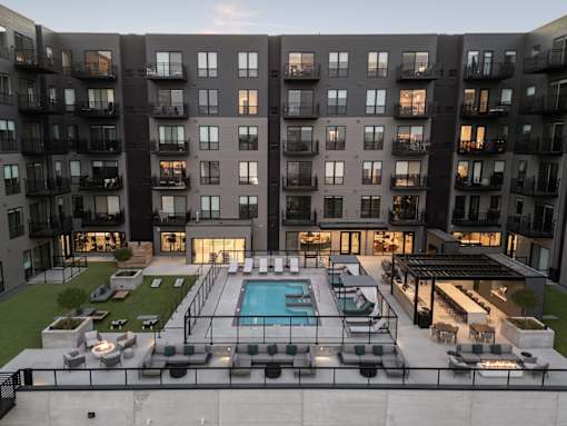 A modern apartment complex with a pool and outdoor seating area.