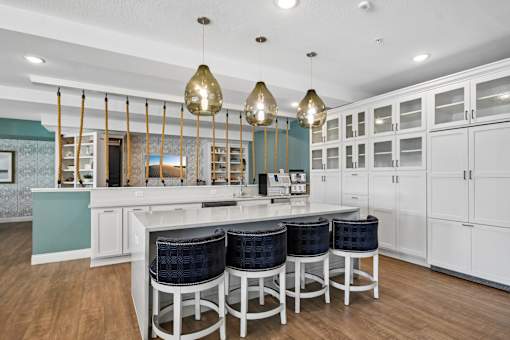 A kitchen with white cabinets and a bar area with blue stools.