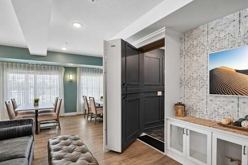 A modern living room with a black door and a large painting on the wall.