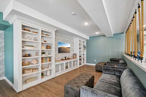 A living room with a white bookcase and a grey couch.