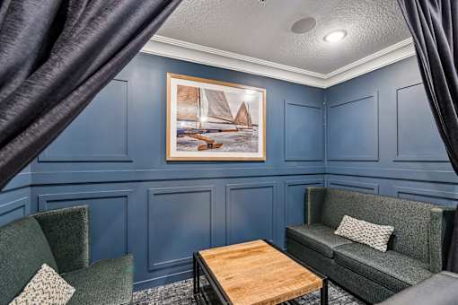 A living room with a green couch, a wooden coffee table, and a painting on the wall.