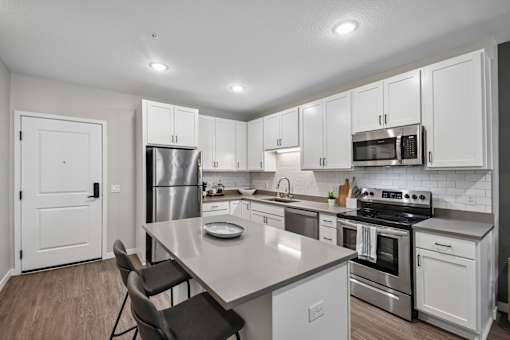 A modern kitchen with white cabinets and stainless steel appliances.