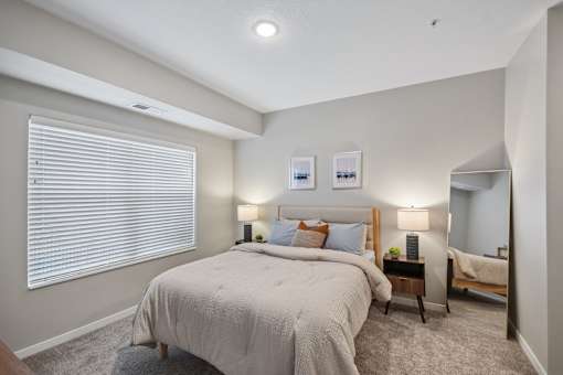 A bedroom with a large bed and a nightstand with a lamp.