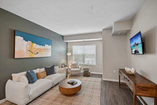 A living room with a white couch and a painting on the wall.