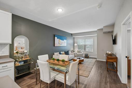 A modern dining room with a glass table and white chairs.