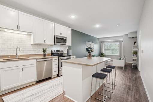 A kitchen with white cabinets and a wooden island.