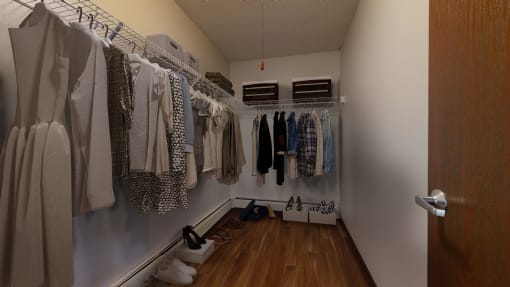 a walk in closet with a lot of clothes hanging on a rack and shoes on the floor