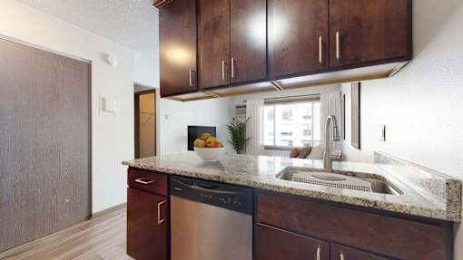 A kitchen with dark wood cabinets and a stainless steel dishwasher.