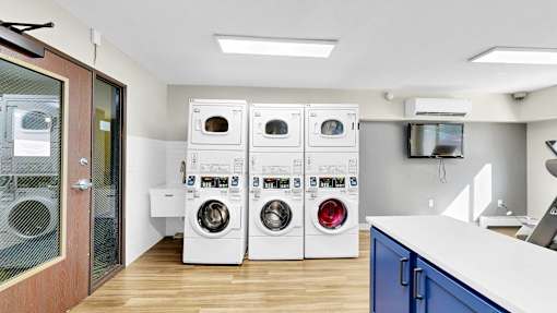 A row of white and red front loading washing machines in a laundry room.