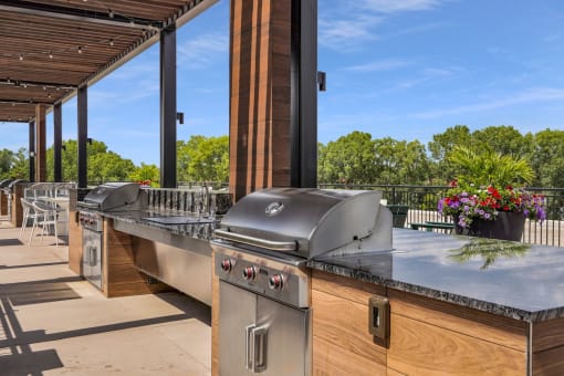 an outdoor kitchen with stainless steel appliances and a bar at The Gateway at West Lake Quarter in Minneapolis, MN