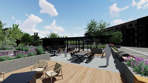 A patio with chairs and tables is surrounded by a wall of flowers. at Olivine Apartments, Minnesota
