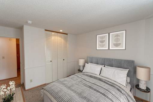 A bedroom with a bed, nightstands, and pictures on the wall.