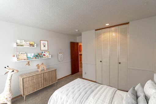 A bedroom with a white bed and a giraffe toy.