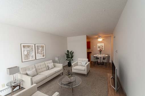 A living room with a white couch and a glass table.