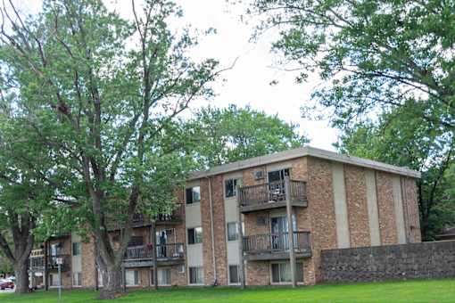 Apartment building with balconies and trees in front.