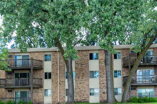 A tall building with balconies and trees in front.