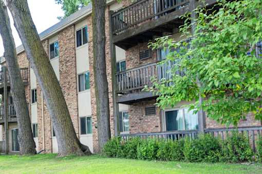 A building with a balcony and a tree in front of it.