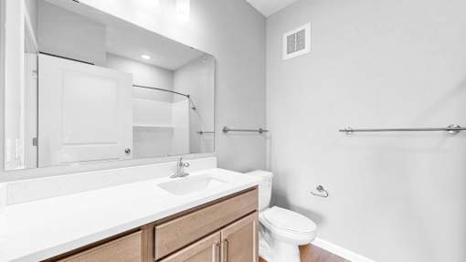 A white bathroom with a toilet, sink, and mirror.
