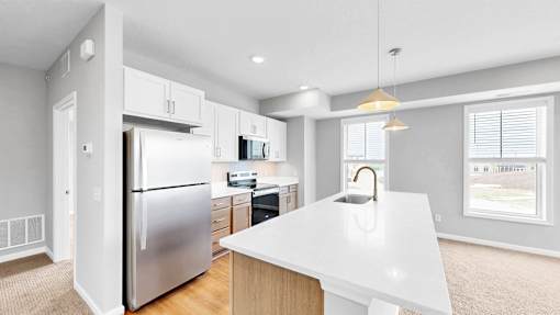 A modern kitchen with a white countertop and stainless steel appliances.
