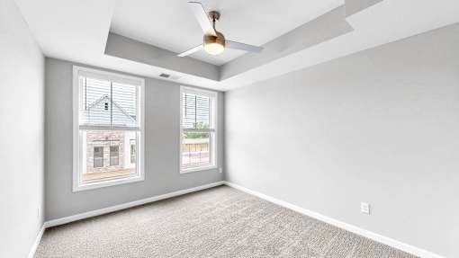 A room with a carpeted floor and a ceiling fan.